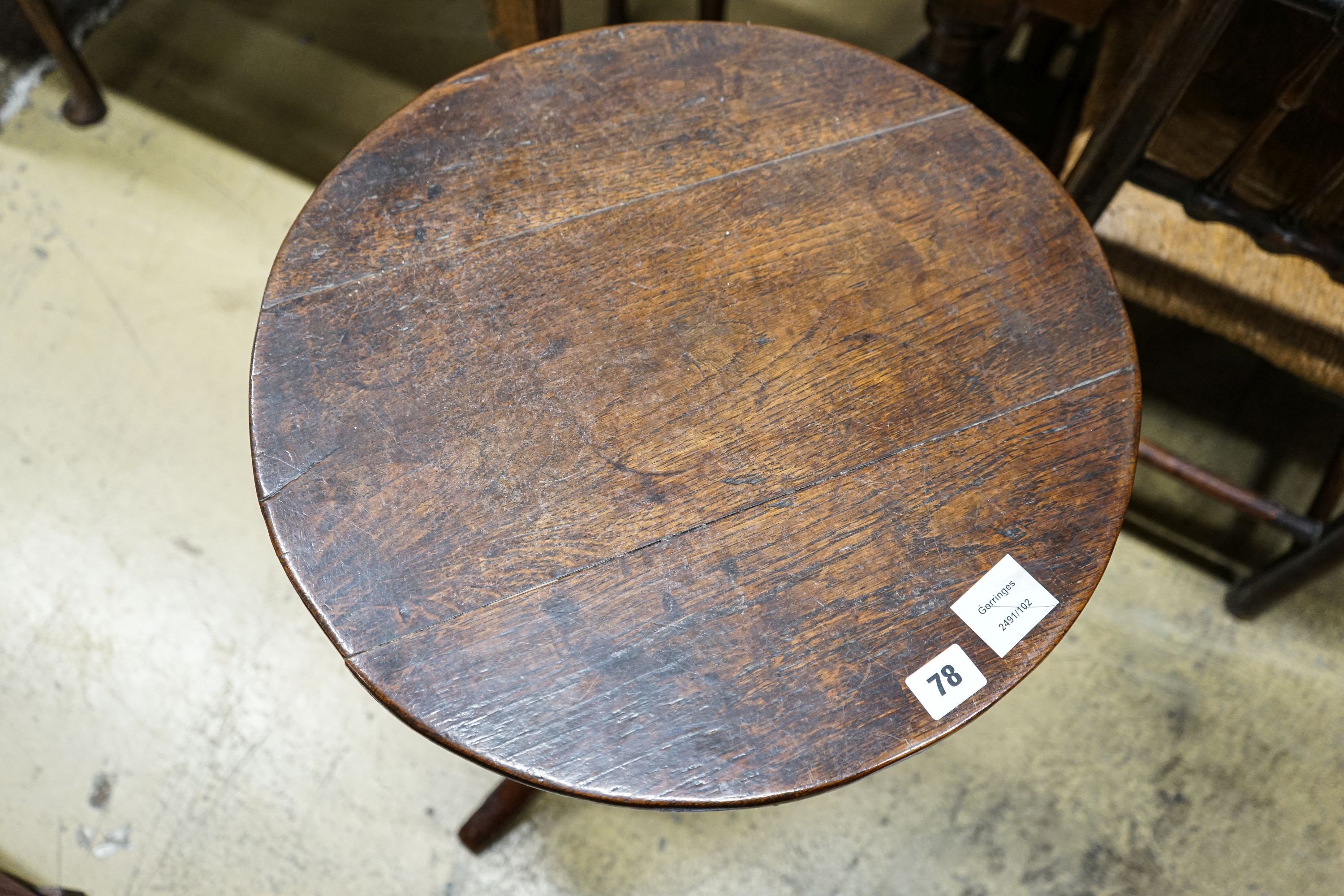 A George III oak tripod table, with circular top and slender baluster stem, diameter 46cm height 72cm